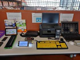 Pokaż zdjęcie: Prezentacja na stoisku sprzętu asystującego dostępnego w OWiT, m.in. linijka brajlowska, luby, tablety, klawiatury.