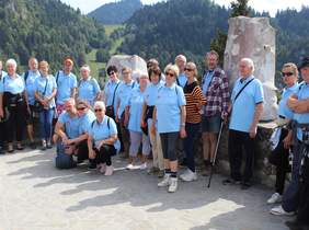 Pokaż zdjęcie: zdjęcie w plenerze na dziedzińcu zamku kilkanaście osób stoi i pozuje do zdjęcia