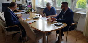 Pokaż zdjęcie: trzech mężczyzn przy stole podpisuje dokumenty