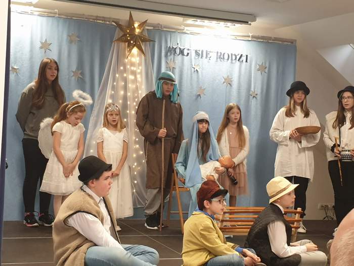 Pokaż zdjęcie: Zdjęcie dzieci biorących udział w przedstawieniu jasełkowym. Na zdjęciu widać Maryję z dzieciątkiem Jezus, Józefa, Pastuszków, aniołki.