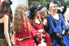 Pokaż zdjęcie: Zdjęcie sześciu młodych kobiet ubranych w piękne, eleganckie suknie, kapelusze, koronkowe rękawiczki.