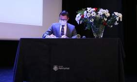 Pokaż zdjęcie: Mężczyzna w maseczce przemawia zza mównicy