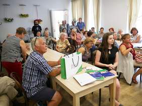 Pokaż zdjęcie: Grupa osób siedząca przy stolikach