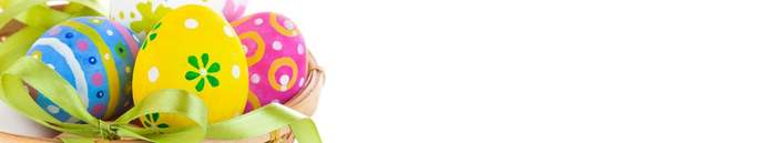 Pokaż zdjęcie: Na białym tle znajduje się wiklinowy koszyk z zieloną wstążką, w którym znajdują się cztery jajka - kolorowe pisanki w kolorze niebieskim z białym, żółtym i różowym. Każda pisanka dodatkowo ma kolorowe zdobienia. Obok koszyka znajdują si
