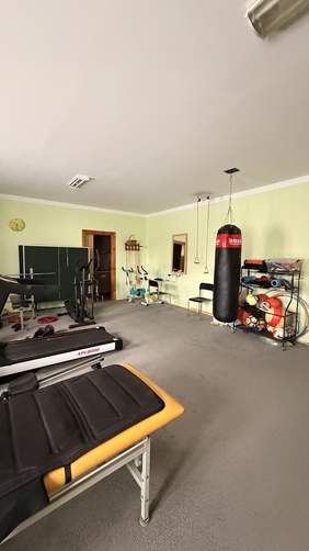 Pokaż zdjęcie: Sala rehabilitacyjna Warsztatu Terapii Zajęciowej wyposażona w sprzęt do ćwiczeń, bieżnię, rower treningowy, stół rehabilitacyjny oraz akcesoria wspierające aktywność fizyczną i usprawnianie uczestników.