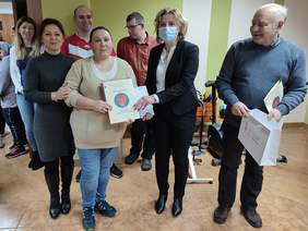 Pokaż zdjęcie: Sześć osób- trzy kobiety i trzech mężczyzn. Kobieta w jasnym swetrze trzyma w dłoni dyplom na którym widzimy czerwone serce na niebieskim kółku. Mężczyzna w granatowym swetrze trzyma bokiem dyplom na którym widzimy czerwone serce na niebieskim