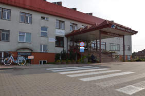 Pokaż zdjęcie: Obok głównego wejścia, do którego prowadzą schody, jest oddzielne wejście na parter budynku z tablicą informującą, że służy one osobom niepełnosprawnym