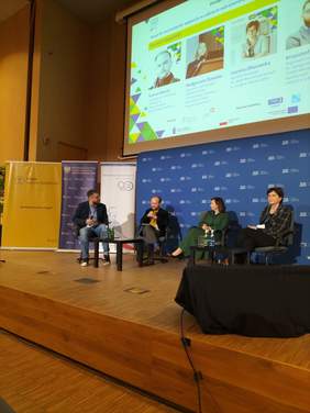 Pokaż zdjęcie: Na scenie w fotelach siedzi czworo panelistów. Od lewej dwóch mężczyzn oraz dwie kobiety.