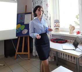 Pokaż zdjęcie: Prelekcja młodej kobiety w niebieskiej bluzce.