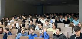 Grupa młodych osób, siedzą na dużej sali