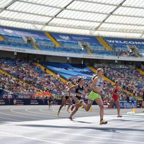 Zawodniczki na bieżni lekkoatletycznej wychodzą z wirażu. 