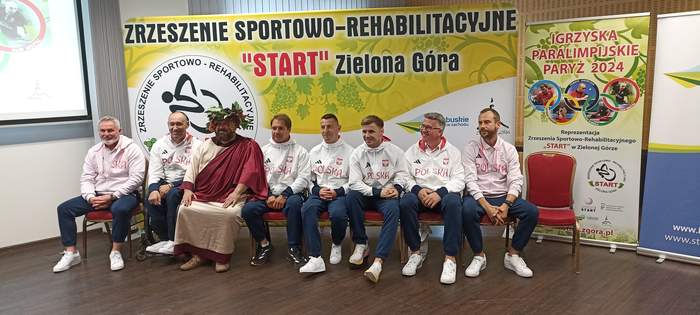 Pokaż zdjęcie: Paralimpijczycy ubrani na sportowo stoją obok siebie ustawieni do zdjęcia, jest z nimi Premier oraz Minister Sportu
