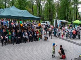 Pokaż zdjęcie: osby siedzą w parku i oglądają występy osób z niepełnosprawnością intelektualną