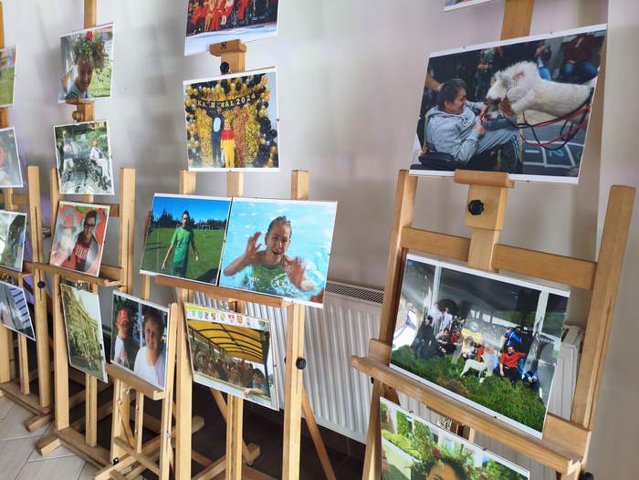 Pokaż zdjęcie: Sztalugi rozstawione w rzędzie przy ścianie. Na sztalugach prezentowane fotografie z trzydziestu lat działalności WTZ