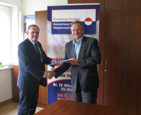 Pokaż zdjęcie: Dyrektor Oddziału Świętokrzyskiego PFRON Andrzej Michalski przekazuje zawartą umowę  Staroście Powiatu Buskiego Jerzemu Kolarzowi 