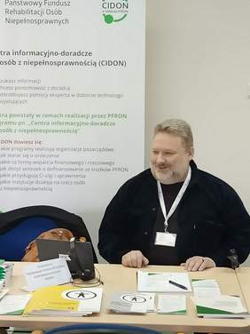 Pokaż zdjęcie: Przedstawiciel PFRON dysponował broszurami i informatorami dotyczącymi pomocy osobom z niepełnosprawnością.