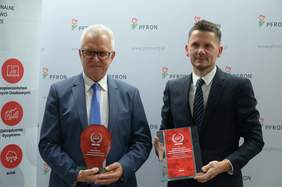 Pokaż zdjęcie: Krzysztof Michałkiewicz - Prezes Zarządu PFRON i Marcin Zastawa - Członek Zarządu PBSG trzymający w rękach wyróżnienie lidera ERM dla PFRON. Panowie stoją na ściance z logo PFRON