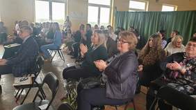 Uczestnicy uroczystości siedzą na krzesłach i oklaskują występy uczestników WTZ-ów