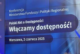 Pokaż zdjęcie: „Zbliżenie na ekran konferencyjny i emitowany slajd: „Konferencja Ministerstwa Funduszy i Polityki Regionalnej. Polski Akt o Dostępności. Włączamy dostępność! Warszawa, 2czerwca 2025”.