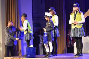 Przedstawiciele policji wręczają prezenty małym artystom 