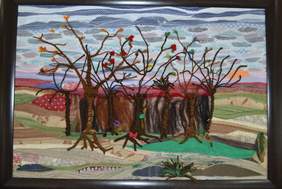 Pokaż zdjęcie: Kolorowe tkaniny tworzą krajobraz wiejski: drzewa, staw oraz pola podzielone plonami.