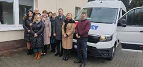 Pokaż zdjęcie: Na tle białego busa do pamiątkowej fotografii ustawili się zaproszeni goście.