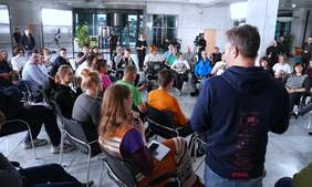 Pokaż zdjęcie: Zdjęcie z nagrań do programu autentyczni, osoby siedzą na krzesłach i rozmawiają ze sobą, w tle widać kamerzystów