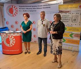 Przedstawiciele organizatorów oraz Dyrektor Kujawsko-Pomorskiego Oddziału PFRON podczas przemówienia, w tle widoczne banery