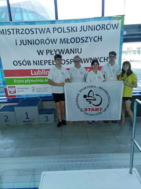 Pokaż zdjęcie: Młodzi pływacy Start Zielona Góra z flagą klubu na tle baneru Mistrzostw