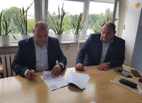 Dwóch mężczyzn siedzi za stołem na którym leżą dokumenty