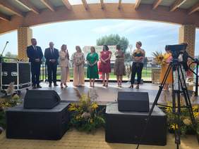 Pokaż zdjęcie: Na scenie stoi grupa ośmiu osób, która składa oficjalne życzenia i gratulacje z okazji jubileuszu.