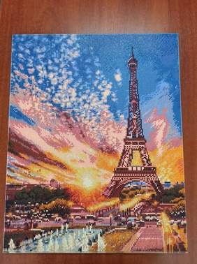 Pokaż zdjęcie: Kolorowa  wieża  Eiffla na tle zachodzącego słońca wykonana metodą haftu