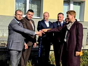 Pokaż zdjęcie: Dwie kobiety i czterech mężczyzn trzyma się kluczyków w uroczystym geście przekazania.