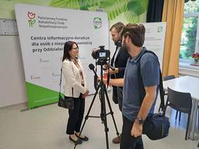 Zastępca Prezesa PFRON podczas udzielania wywiadu dla lokalnej telewizji, w tle ścianka CIDON PFRON