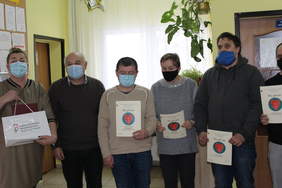 Pokaż zdjęcie: .Sześć osób w maseczkach- dwie kobiety i czterech mężczyzn . Kobieta po lewej stronie fotografii trzyma w dłoni białą torbę z czerwono- zielonym kwiatkiem i napisem Państwowy Fundusz Rehabilitacji Osób Niepełnosprawnych . Cztery pozostałe oso