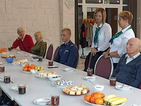 Pokaż zdjęcie: UCzestnicy spotkania przy stole w trakcie spotkania z policjantem