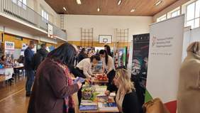 Pokaż zdjęcie: Przy stoisku stoją osoby zainteresowane ofertą funduszu.