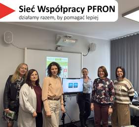 Pokaż zdjęcie: Na górze, na białym tle, widoczny jest czerwony, trójkątny element. Obok znajduje się tekst: 'Sieć Współpracy PFRON', a poniżej napis: 'działamy razem, by pomagać lepiej'. Zdjęcie grupowe sześciu kobiet stojących w sali szkoleniowej przy tablicy. Pomieszczenie ma jasnoszare ściany, na ścianie widać projektor oraz dwa głośniki. Po prawej stronie są pionowe żaluzje przy oknie i fragment biurka. Kobiety stoją w jednym rzędzie, uśmiechnięte. Na tablicy za nimi jest wyświetlony slajd