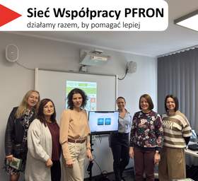 Na górze, na białym tle, widoczny jest czerwony, trójkątny element. Obok znajduje się tekst: 'Sieć Współpracy PFRON', a poniżej napis: 'działamy razem, by pomagać lepiej'. Zdjęcie grupowe sześciu kobiet stojących w sali szkoleniowej przy tablicy. Pomieszczenie ma jasnoszare ściany, na ścianie widać projektor oraz dwa głośniki. Po prawej stronie są pionowe żaluzje przy oknie i fragment biurka. Kobiety stoją w jednym rzędzie, uśmiechnięte. Na tablicy za nimi jest wyświetlony slajd