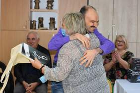 Pokaż zdjęcie: Młody mężczyzna podczas wręczania dyplomu ukończenia szkoły przytula się do nauczycielki