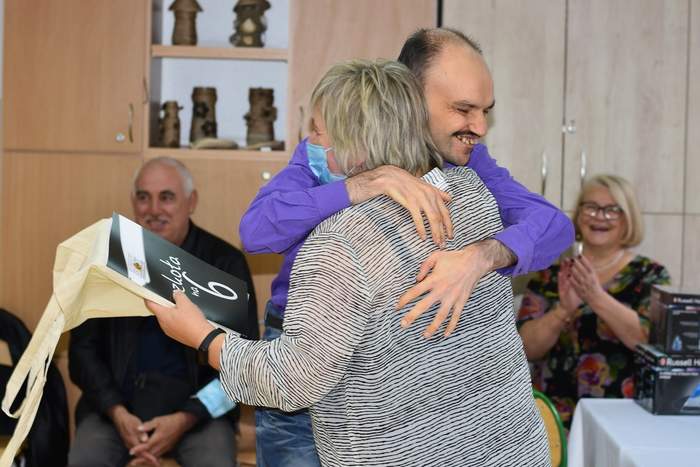 Pokaż zdjęcie: Młody mężczyzna podczas wręczania dyplomu ukończenia szkoły przytula się do nauczycielki