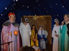 Pokaż zdjęcie: na zdjęciu grupa osób przebrana w szaty trzech Króli oraz stroje aniołów przedstawia Jasełka 