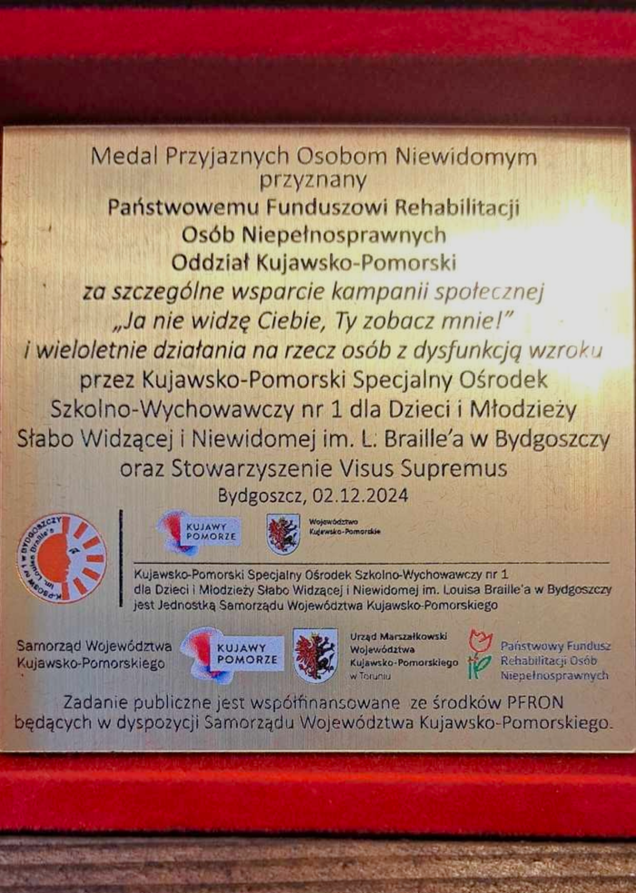 Wygrawerowana tabliczka, umieszczona w pudełku, w którym znajduje się medal