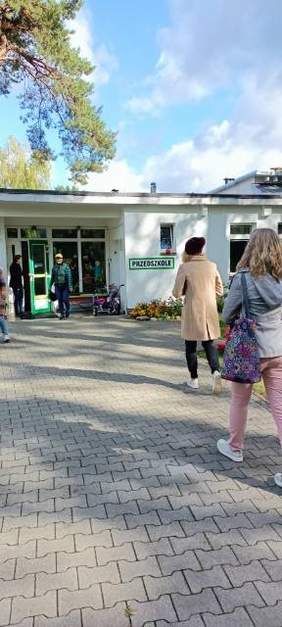 Pokaż zdjęcie: Osoby wchodzące do budynku przedszkola