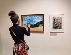 Pokaż zdjęcie: Laureatka robi zdjęcie jednej z prac prezentowanych na wystawie