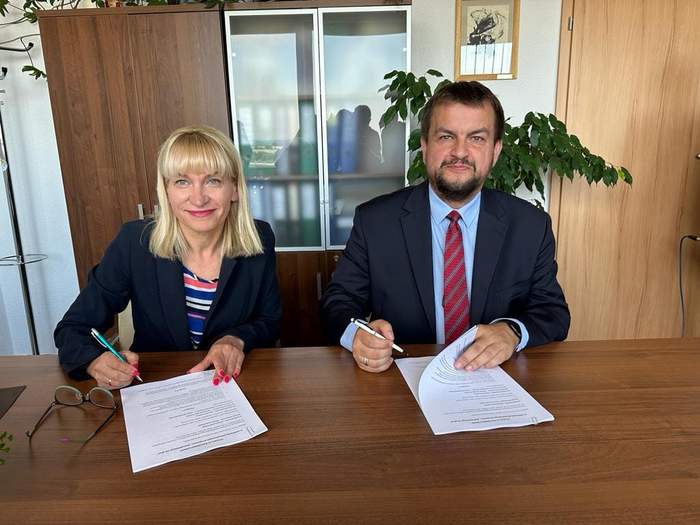 Pokaż zdjęcie: Dyrektor Oddziału Lubuskiego PFRON oraz Starosta Nowosolski w trakcie podpisywania umowy, są przy biurku z długopisami w ręku, są uśmiechnięci