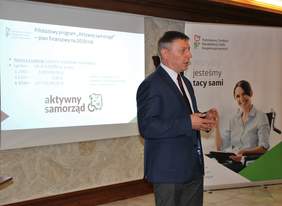 Pokaż zdjęcie: Krzysztof Kaca Naczelnik Wydziału ds. Projektów z Departamentu ds. Programów PFRON na tle ekranu multimedialnego