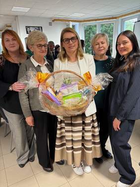 Pokaż zdjęcie: Pięć stojących w grupie kobiet. Dyrektor OSW w Laskach, przedstawicielka OWiT oraz trzy przedstawicielki PFRON. Kobieta stojąca pośrodku trzyma w rękach kosz ze słodyczami.