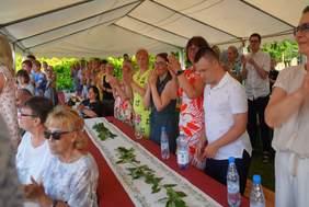 Pokaż zdjęcie: osoby siedzą i stoją oklaskują występ uczestników Warsztatu Terapii Zajęciowej