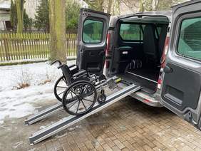 Pokaż zdjęcie: Tył busa z rozłożonymi szynami na którym stoi wózek inwalidzki